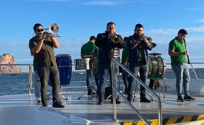 Músicos con instrumentos de viento y percusión en una embarcación de Mazatlán, México.
