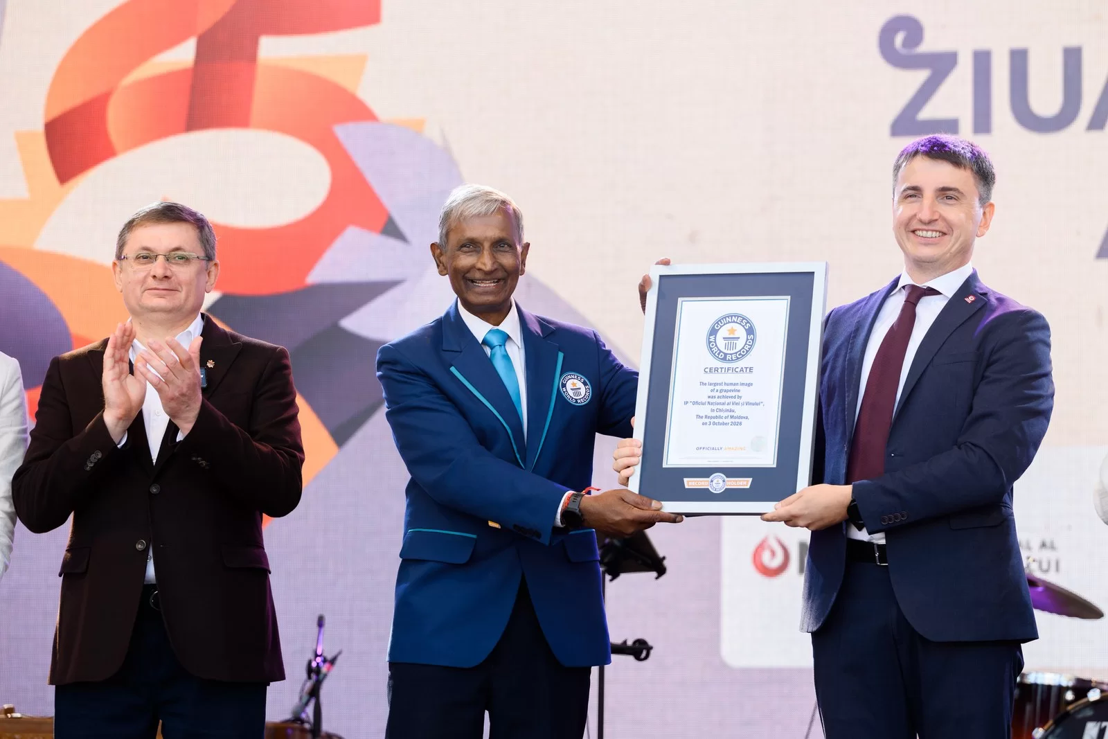 El adjudicador de Guinness World Records sostiene el certificado del récord de la vid humana en el escenario del Día Nacional del Vino en Chișinău